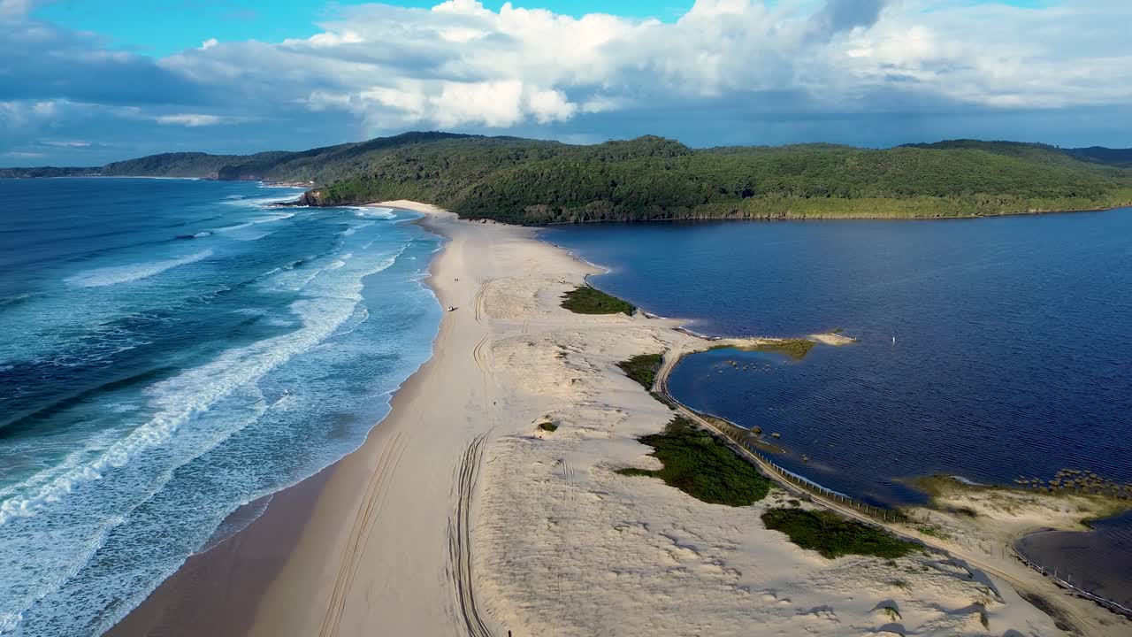 Drone aerial landscape of ocean waves breaking on coastline headland in Cellito Sandbar Beach town suburbs with bushland forest and Smiths Lake inlet channel lagoon in Australia Forster travel tourism