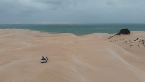 white 4x4 car driving on dunes at western australia, aerial