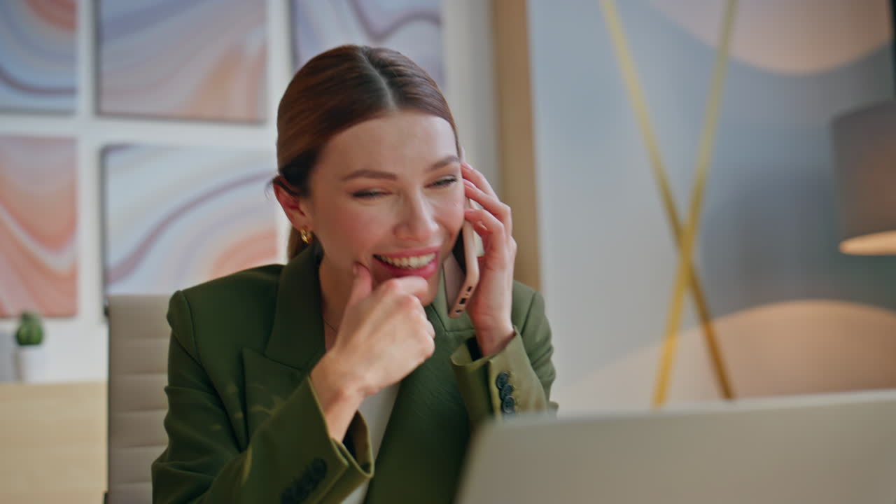 Smiling executive speaking mobile phone in modern office closeup. Woman laughing