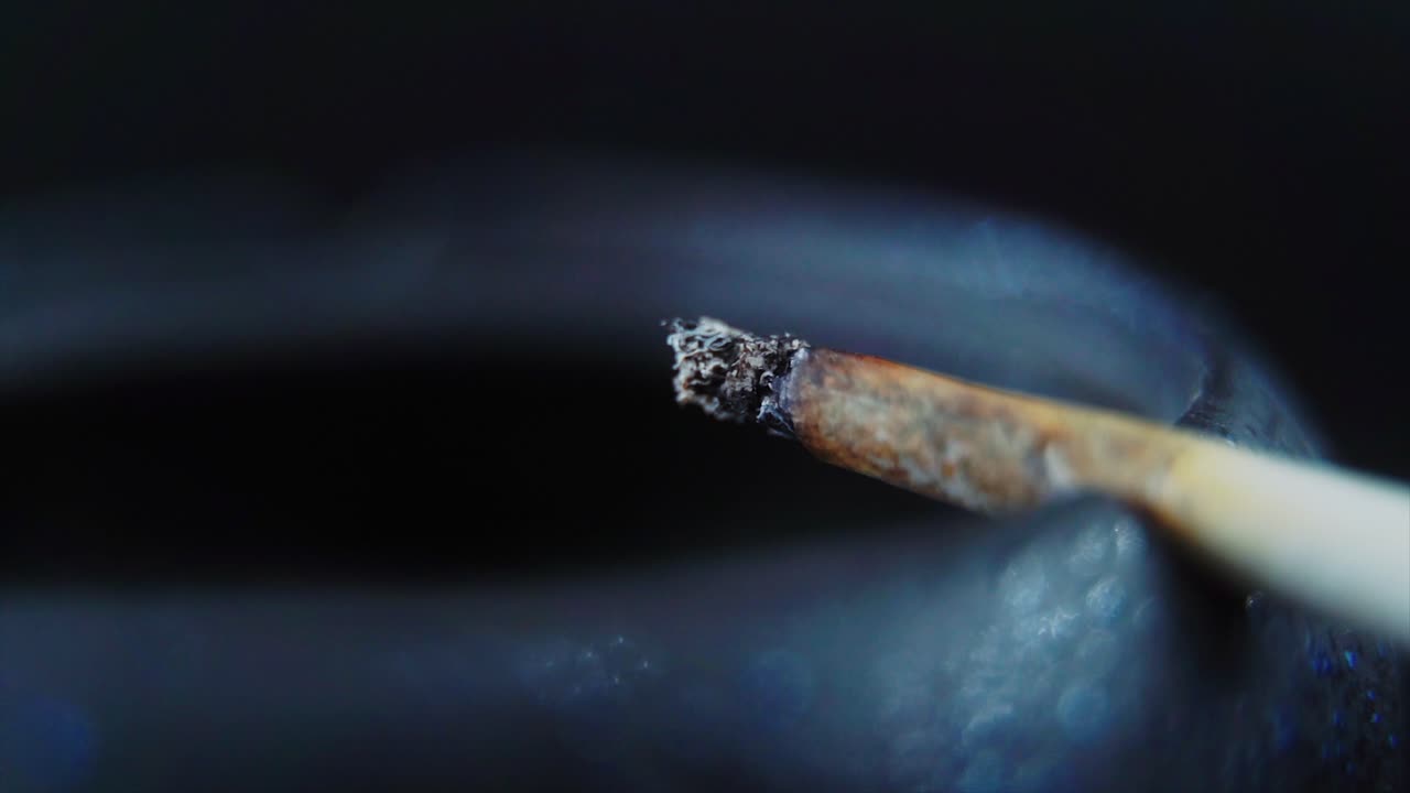 un primer plano macro de residuos de ceniza de un cigarrillo en un cenicero de piedra negra, video de 4k en cámara lenta, humo blanco 6