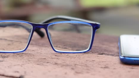 blue glasses and smartphone on a wooden table