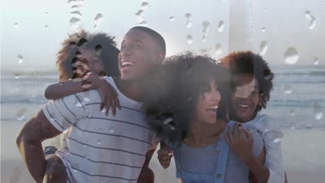 animation of droplets over happy african american family at beach on sunny day smiling over sea