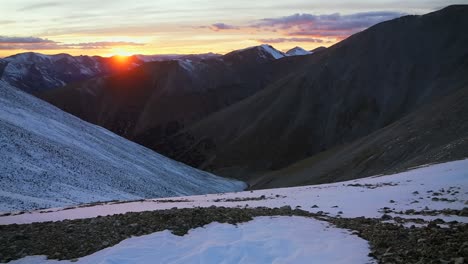 Mt Mount Shavano glowing Rocky Mountains sunset Elbert Huron La Plata Tabeguache Antero Peak Colorado aerial drone fall autumn snow Sawatch Range top of summit sun on horizon clouds pan left motion