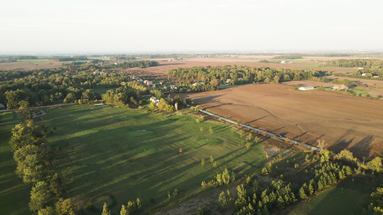 Aerial Countryside Landscape View in Pelham Ontario Canada in Autumn Season, Rural Road and Car Passing Surrounded by Vast Green Golf Field Farmlands and Agricultural Lands, Skyline in Horizon