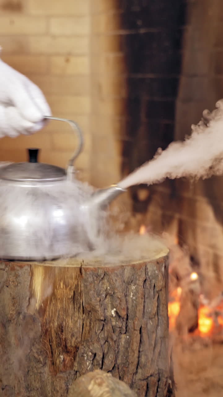 Close up of steaming teapot. Santa Claus's hand is taking the kettle. New Year and Christmas concept. Feast is coming. Vertical video