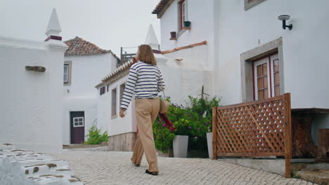 girl walk mediterranean town with white wash houses on summer vacation vertical.