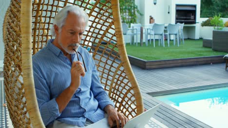hombre mayor leyendo un libro mientras está sentado en una silla colgante 4k