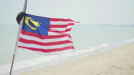 una bandera nacional de malasia ondeando en la costa ventosa