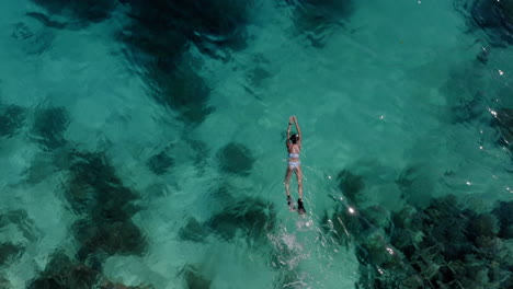 A-woman-is-swimming-and-free-diving-over-the-reefs-in-Raja-Ampat,-West-Papua