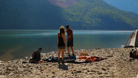 pareja de excursionistas preparando una tienda cerca de la orilla del río 4k