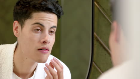 focused biracial man inspecting face in bathroom mirror, slow motion