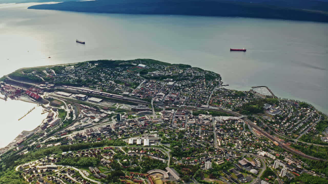 Aerial drone shot over the city of Narvik in Norway. High view of the scenic green landscape, the sea and the nordic fjords.