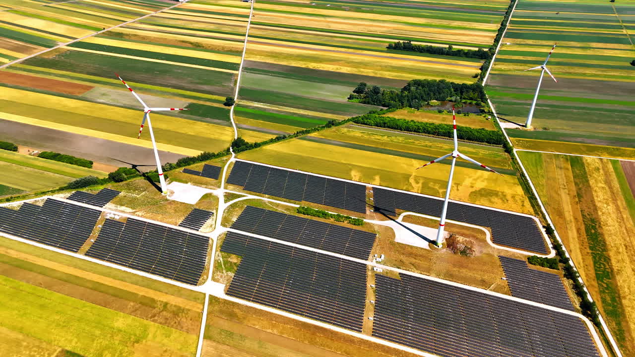 Modern wind turbine produce renewable energy in the fields. Ground under them is covered with solar panels. Aerial view