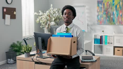 man with afro hair quits company job walks out of office with things packed in box leaves corporation quits responsibilities retires leaves social room