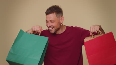 happy smiling young man showing shopping bags, advertising discounts, amazed with low prices