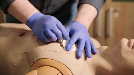 el médico táctico cubre la herida con un vendaje en el maniquí.