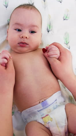 surgeon moves baby's hands back and forth. child is staying calm and watching the doctor with curiosity. view from above. vertical video