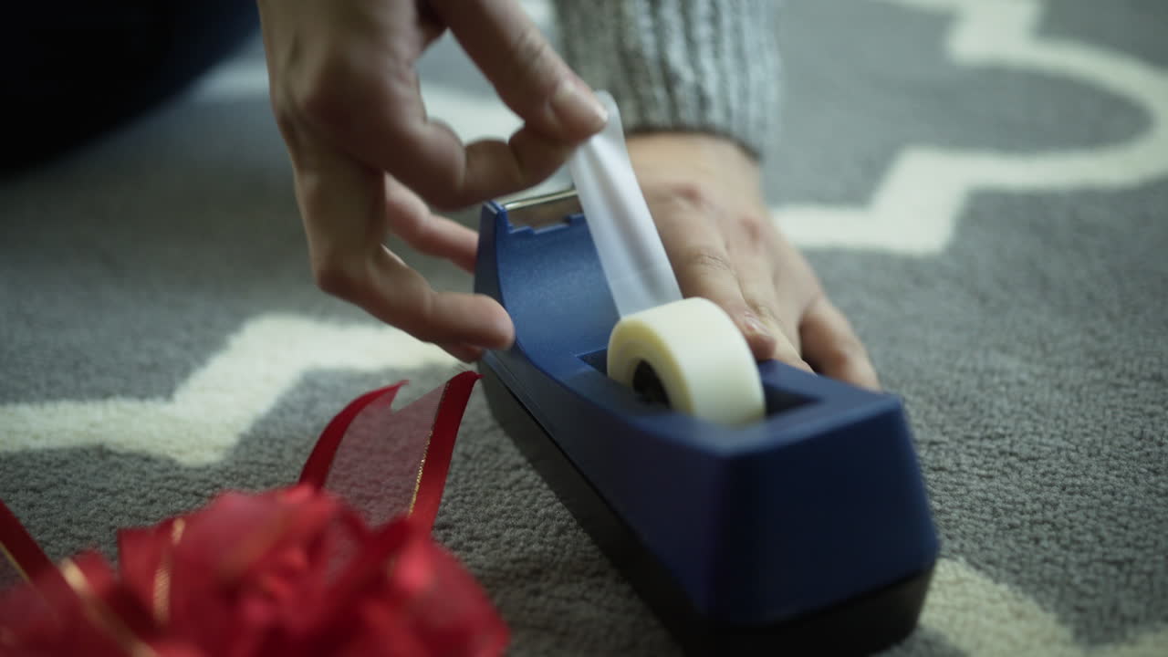 la mujer saca la cinta del dispensador de cinta para envolver los regalos navideños, cierra