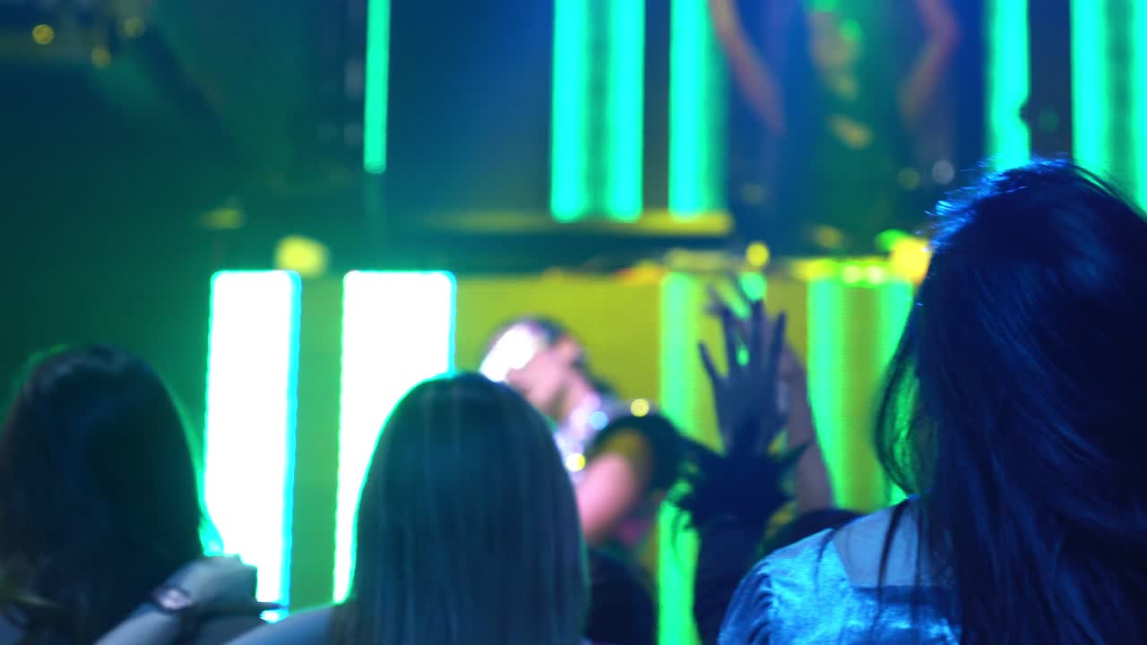 gruppo di persone che ballano in un discoteca al ritmo della musica del dj sul palco