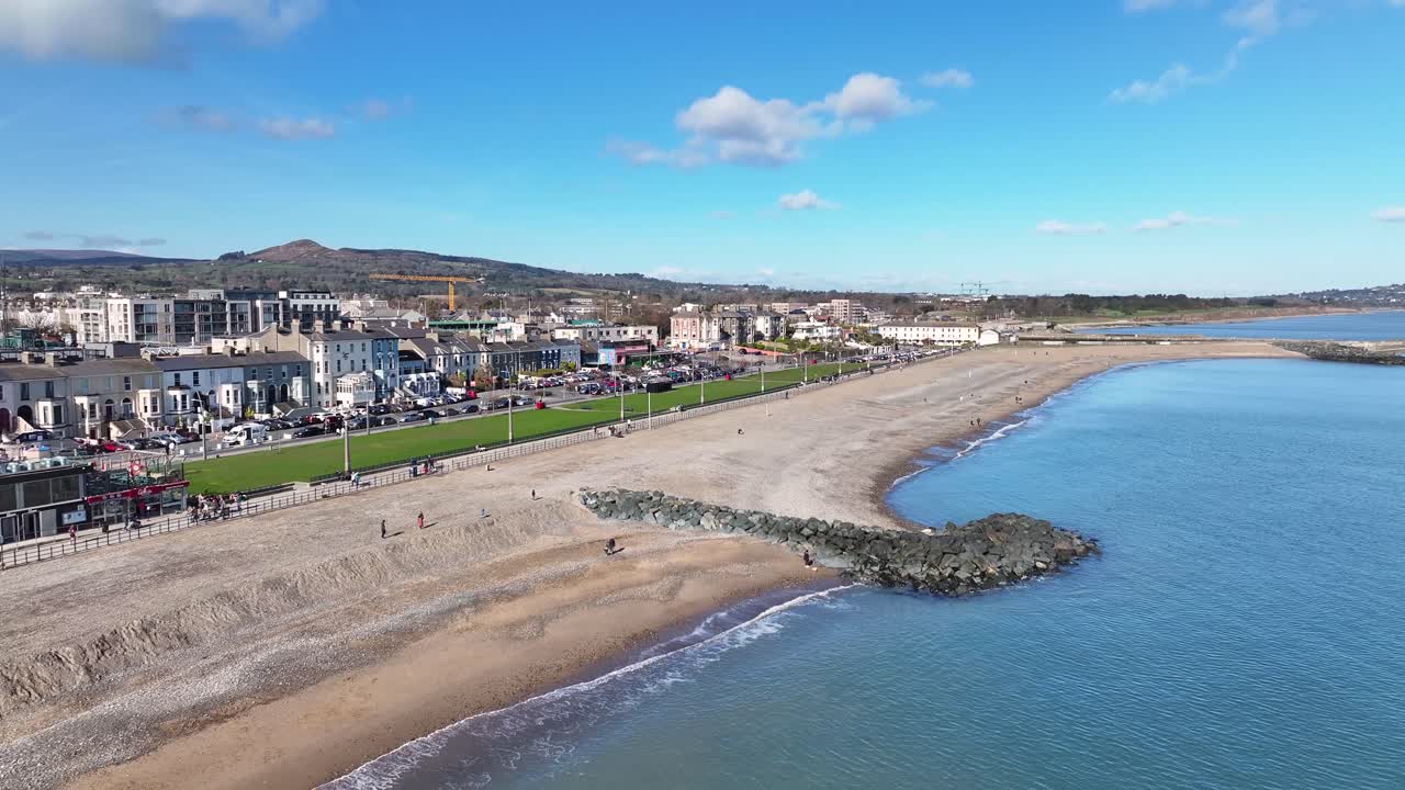 Luftoptagelse, der afslører Bray strandpromenade og mennesker, der nyder en solskinsdag i Irland. Kystby