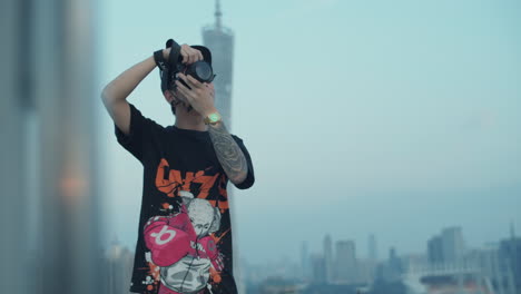 Young-asian-photographer-with-tattoo-captures-urban-downtown-cityscape-from-the-rooftop-in-the-early-morning