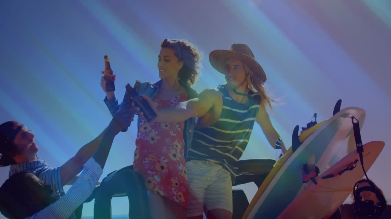 Tre amici viaggiano sul cassone di un camion con tavole da surf appoggiate, si passano e brindano con la birra.