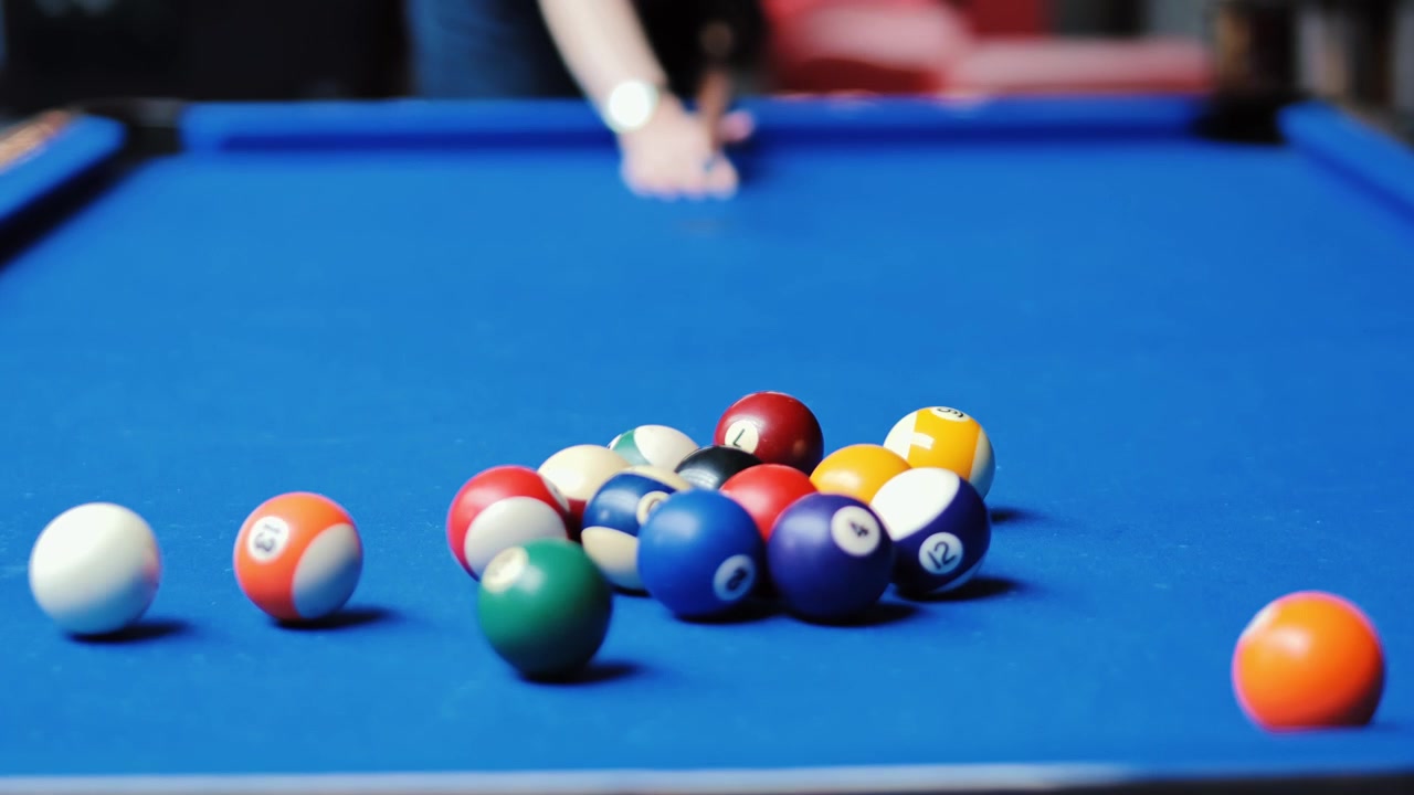 Cue ball strikes colorful rack as player begins competitive billiards game