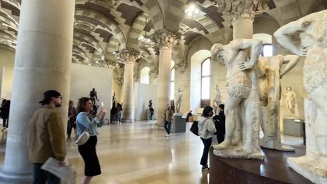 people exploring sculptures in louvre museum, paris