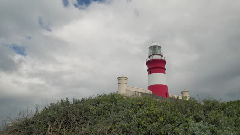 Timelapse:-El-Segundo-Faro-Más-Antiguo-De-Sudáfrica-Sigue-En-Funcionamiento,-El-Faro-De-Cape-Agulhas-Con-Nubes-Moviéndose-En-El-Fondo