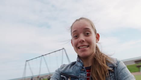 front view of a caucasian looking at camera taking selfie on a merry-go-round