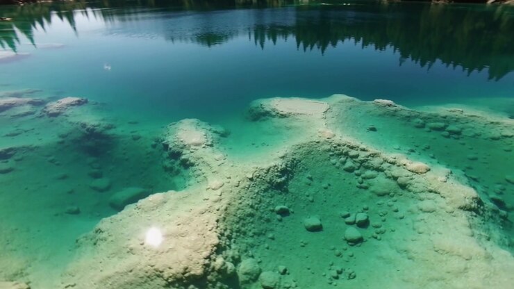 Starting glide drone revealing turquoise water over mounds and boulders showing central formation