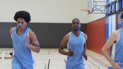 Focussed-diverse-male-basketball-team-training,-sprinting-on-indoor-court,-slow-motion