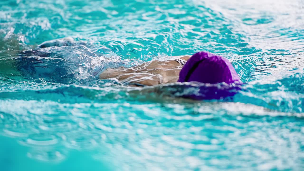 Uimari violetissa uimalakissa uimassa vapaauintia hidastettuna