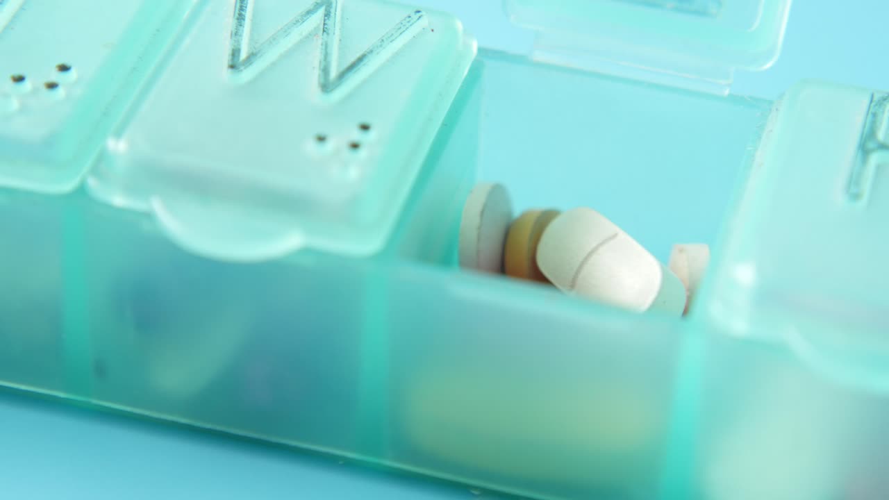 내부에 다양한 약이 들어있는 주간 약 조직자의 클로즈업