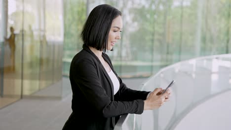 mujer de negocios que usa un teléfono inteligente en un edificio de oficinas moderno