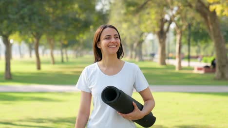 Chica-India-De-Yoga-Caminando-Con-Estera-De-Yoga-En-Un-Parque-Por-La-Mañana