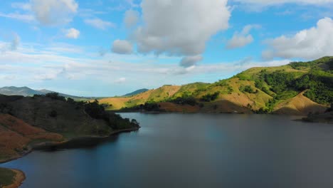 aerial drone shot flying through a lake between mountains revealing a dam