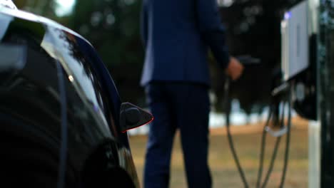 Businessman-charging-electric-car-at-charging-station-4k