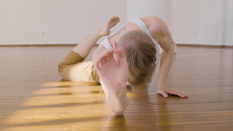 giovane concentrato in abbigliamento casual che esegue una danza contemporanea sul pavimento in studio 1