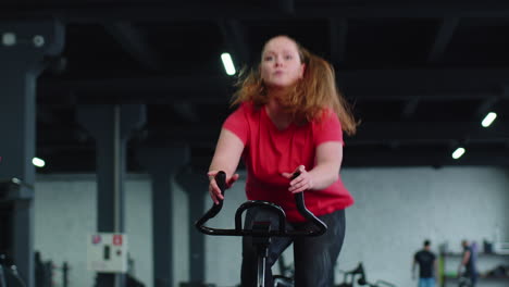 mujer atlética montando una bicicleta estacionaria de giro rutina de entrenamiento en el gimnasio, pérdida de peso en el interior