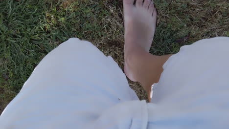 pov view, man with bermuda shorts and barefoot walking on dry grass