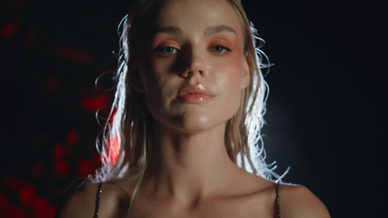 Closeup party girl face in projector light. Seductive beautiful blonde posing