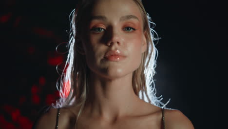 la cara de la chica de la fiesta en primer plano en la luz del proyector. seductora hermosa rubia posando
