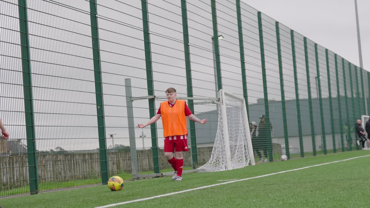 Substitute players, wearing bibs, chatting, soccer ball kicking