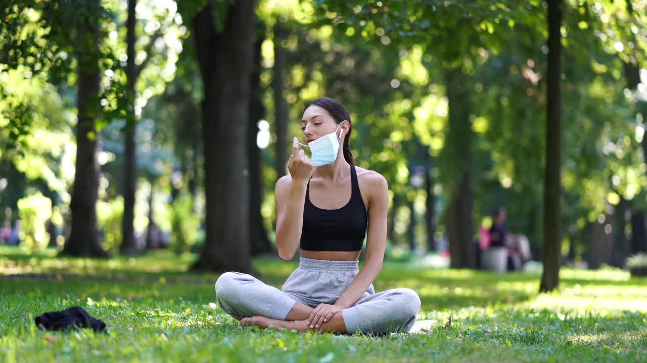 mujer meditando en un parque con una máscara