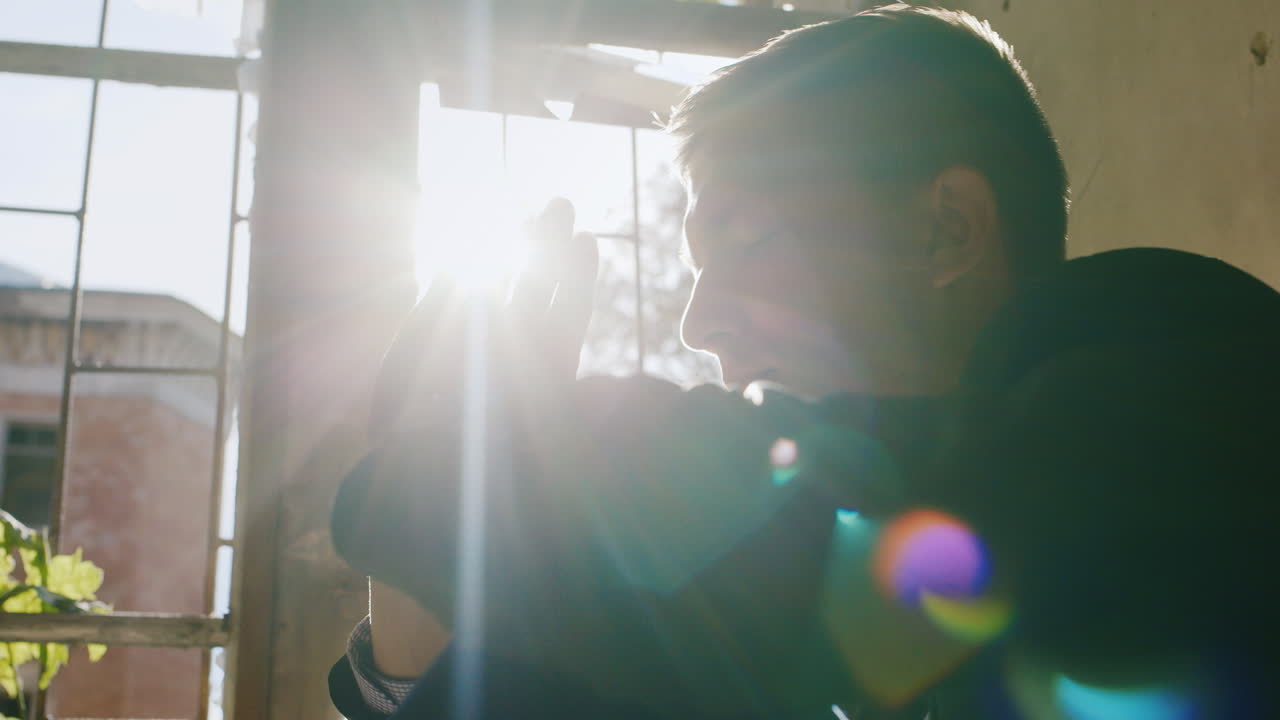 joven sentado en el alféizar de la ventana con un propósito o rezando