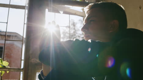 Young-Man-Sitting-On-The-Windowsill-Purposeful-Or-Praying