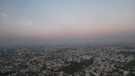 high-altitude aerial footage of a contemporary indian city illuminated by a pink-hued evening sky