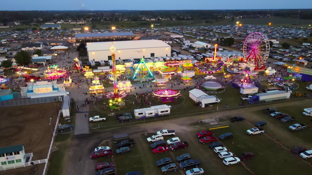 Carnival at the Monroe County Fairgrounds with glowing lights and lots of people, aerial view