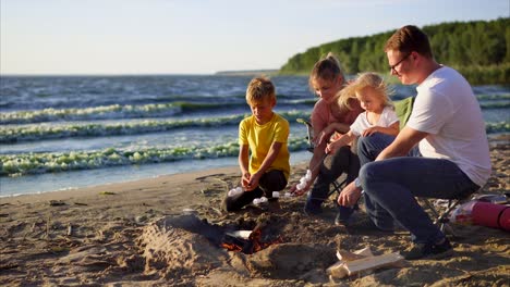 family roasting marshmallows on the beach